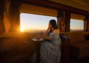 Woman enjoying sunset views from the lounge aboard The Ghan.
