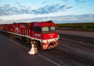 A couple shares a moment beside The Ghan locomotive at sunset.