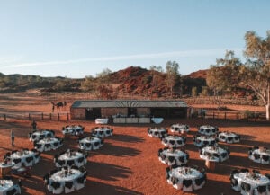 Round banquet tables set up for outdoor dining in the red dust of the Alice Springs Telegraph Station.