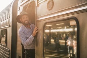 Friendly train host welcoming guests aboard the Great Southern at a regional station.